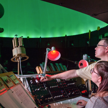2 people sit at a control center inside the VCSU planetarium