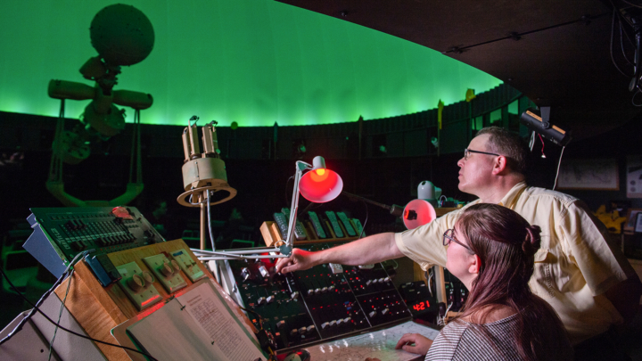 2 people sit at a control center inside the VCSU planetarium