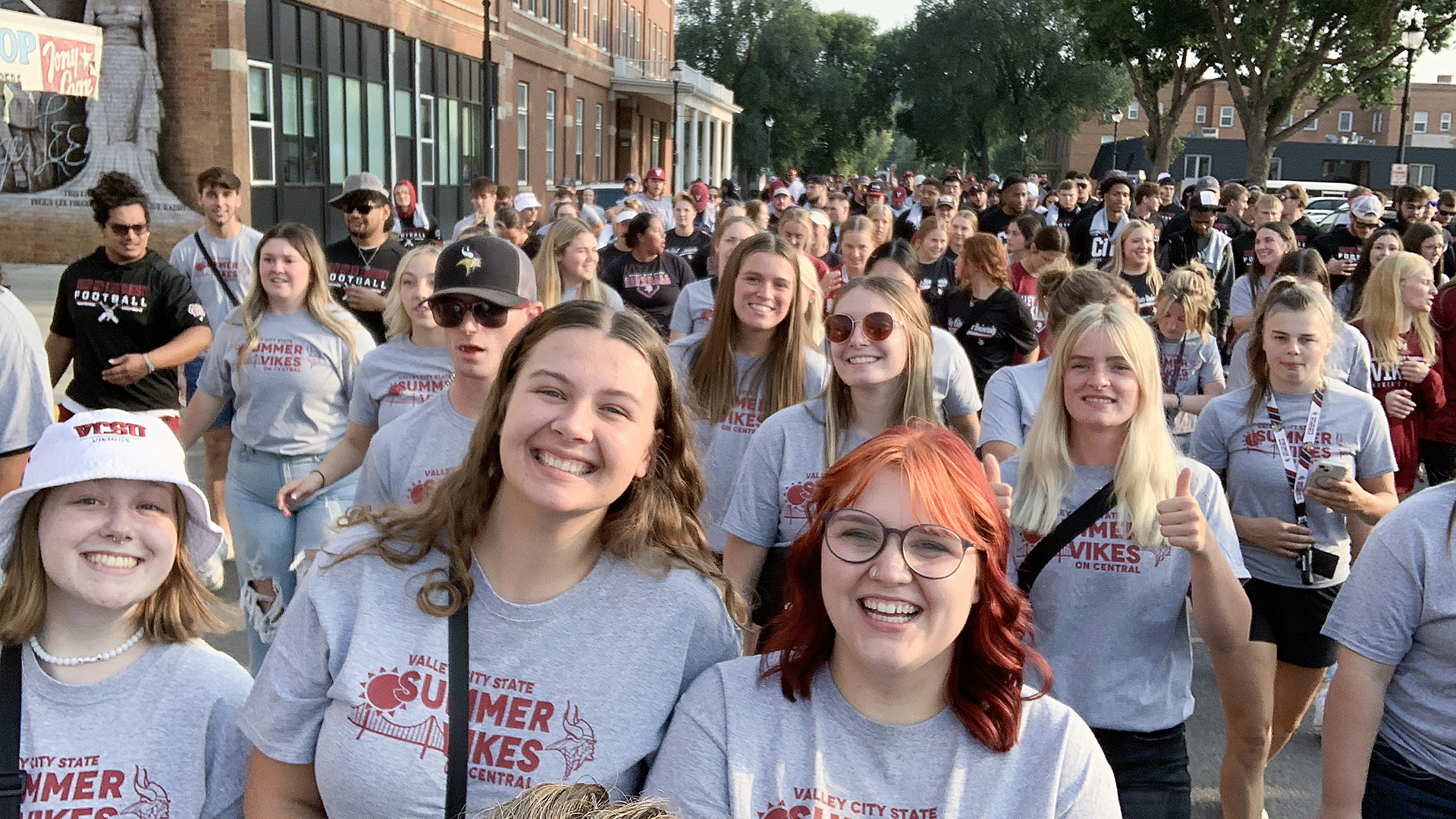 Hundreds of VCSU students smile and walk to downtown Valley City for the annual Summer Vikes on Central event with the Valley City community.