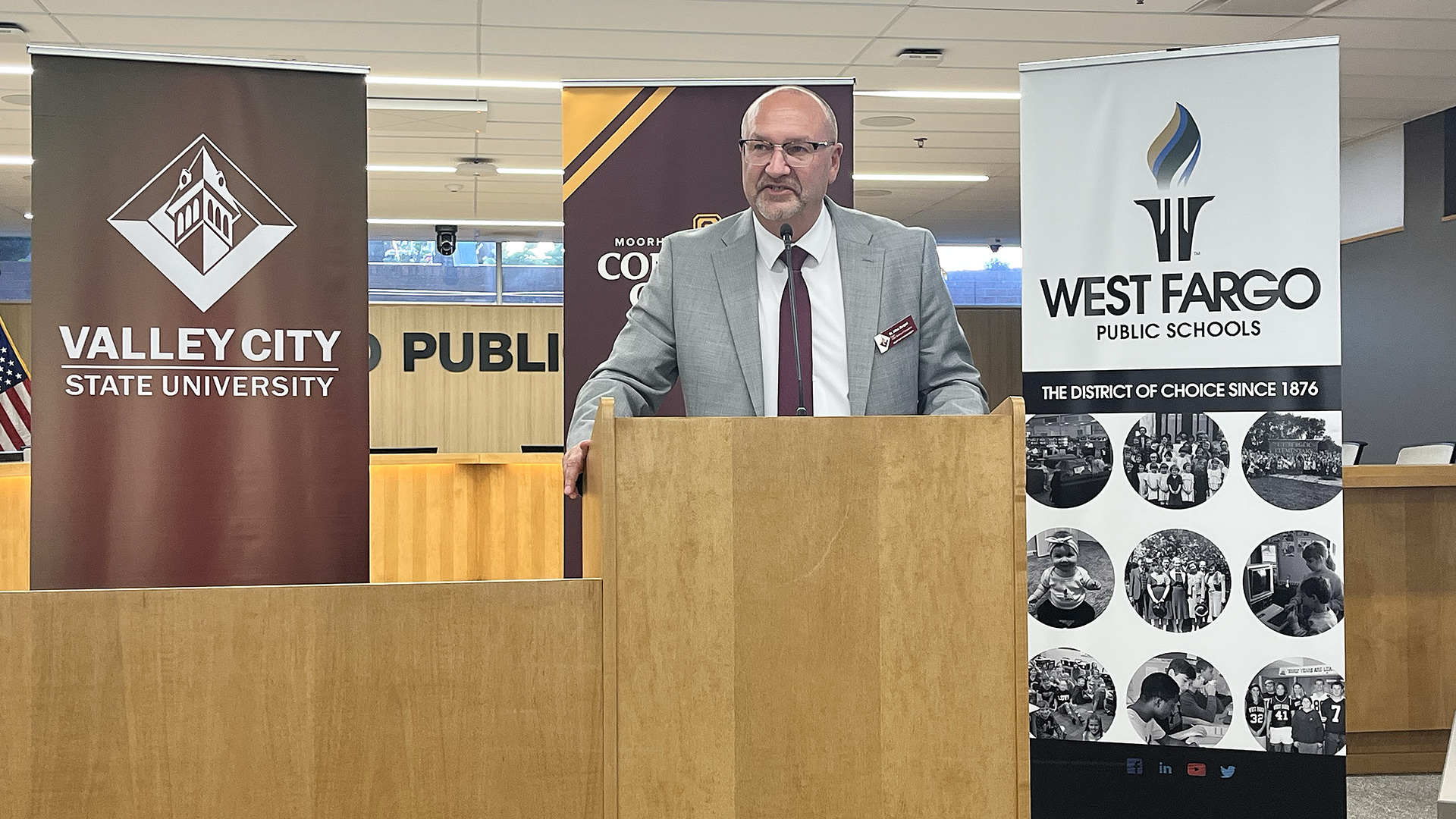 Dr. Allen Burgad speaks at a podium in front of a VCSU banner
