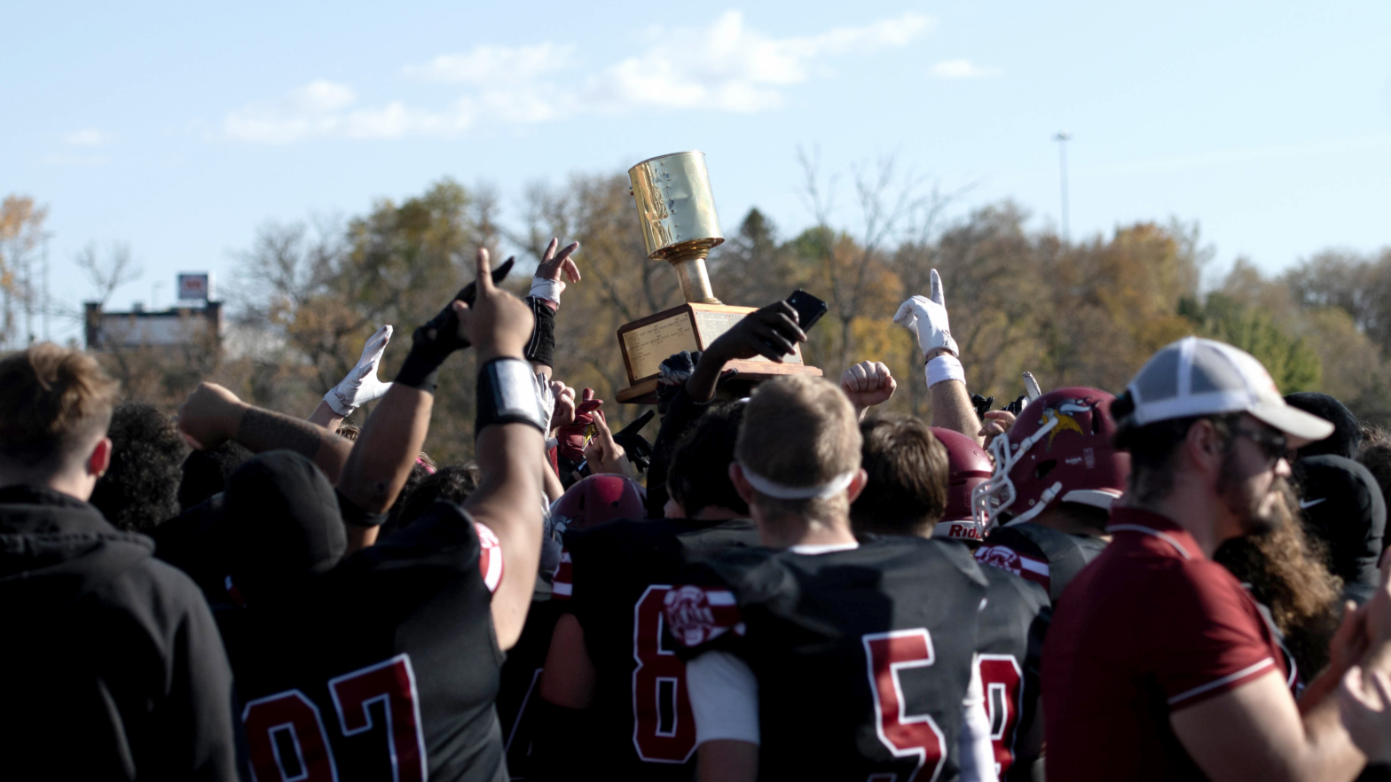 football team celebrating holding up paint bucket trophy