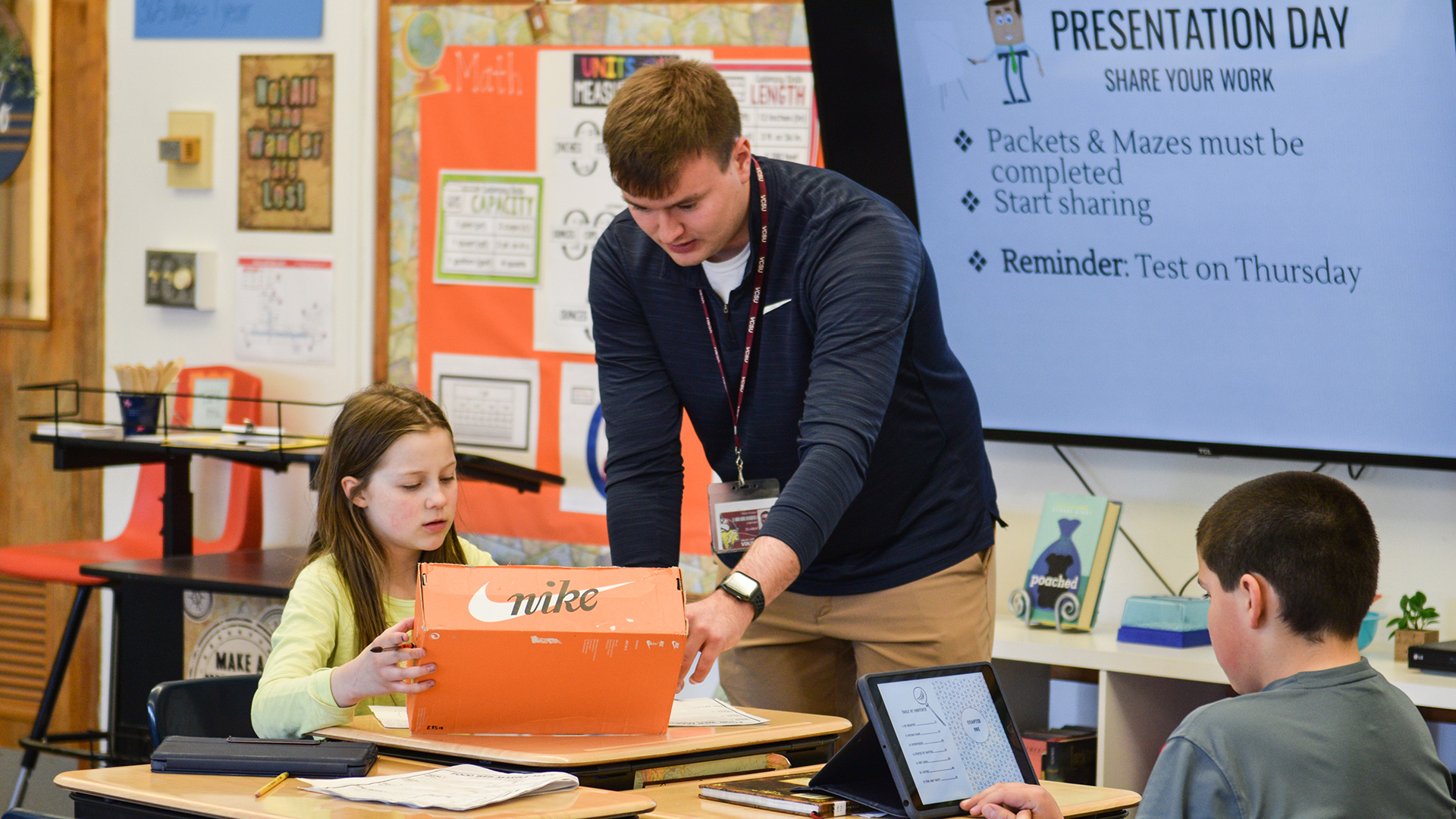 VCSU alumni Hunter Sand teachers to 2 elementary students in a classroom.