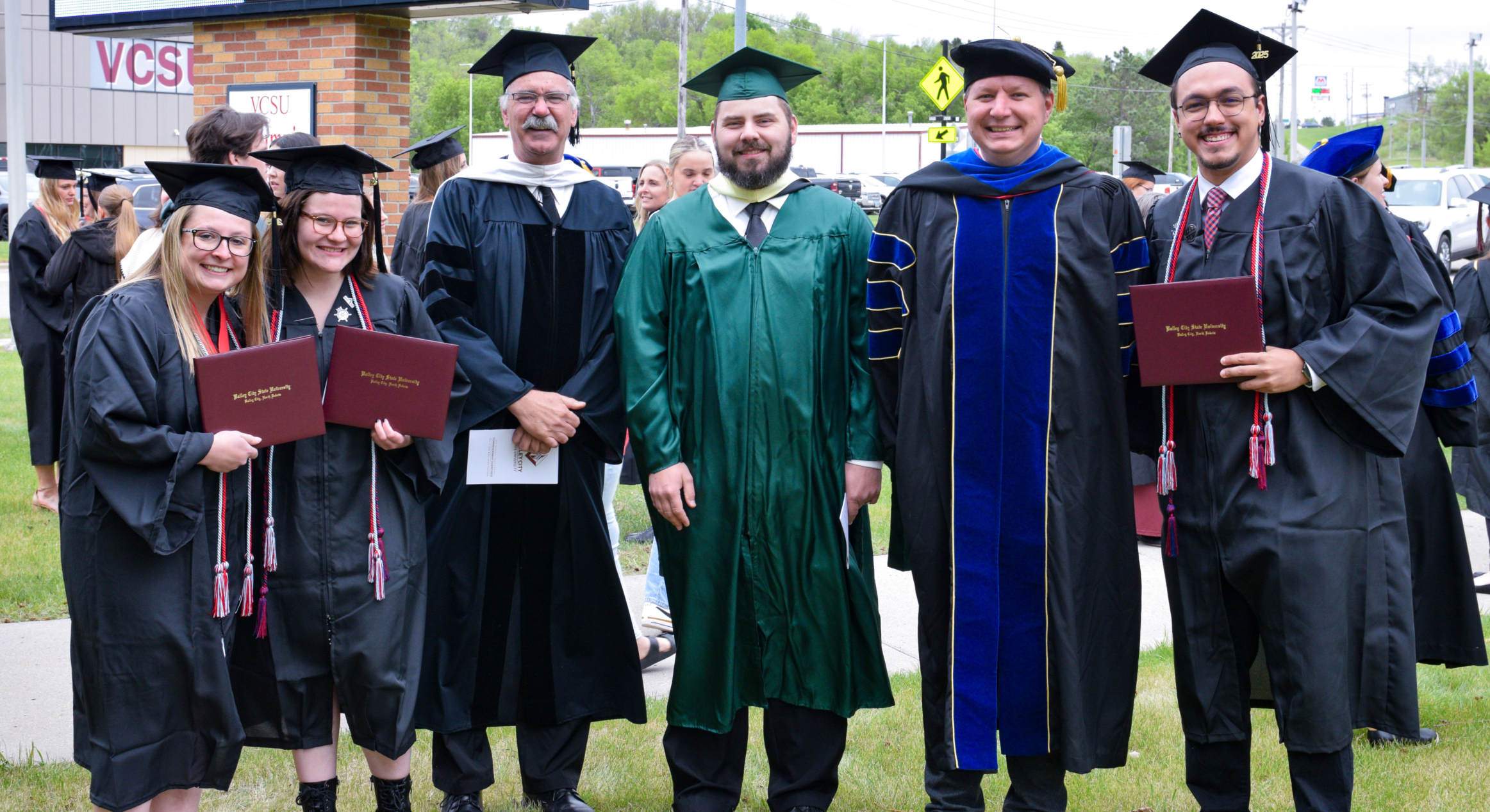 Grace Reep alongside other graduates and professors smiling at the camera