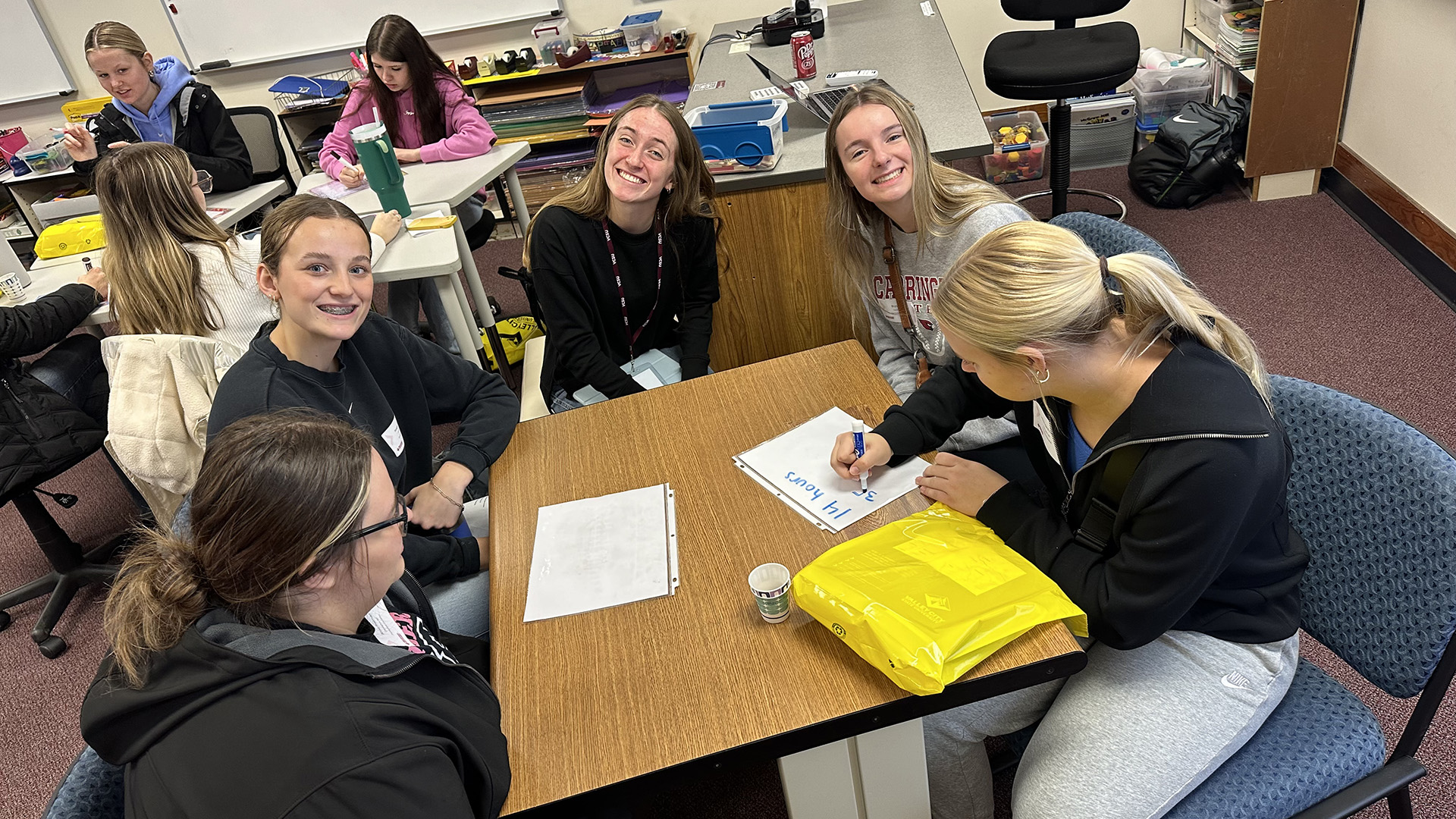 5 high school students sit at a table and work on a project during a visit to VCSU