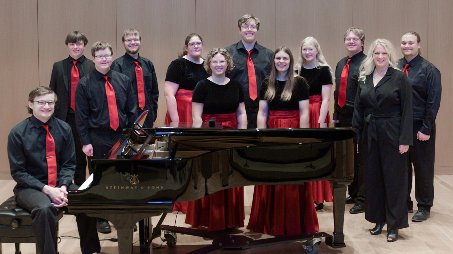 Members of the VCSU Concert Choir stand on stage in the CFA around a black piano
