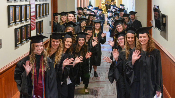 VCSU graduates smile in black caps and gowns while waiting for the 2023 commencement exercises to start.