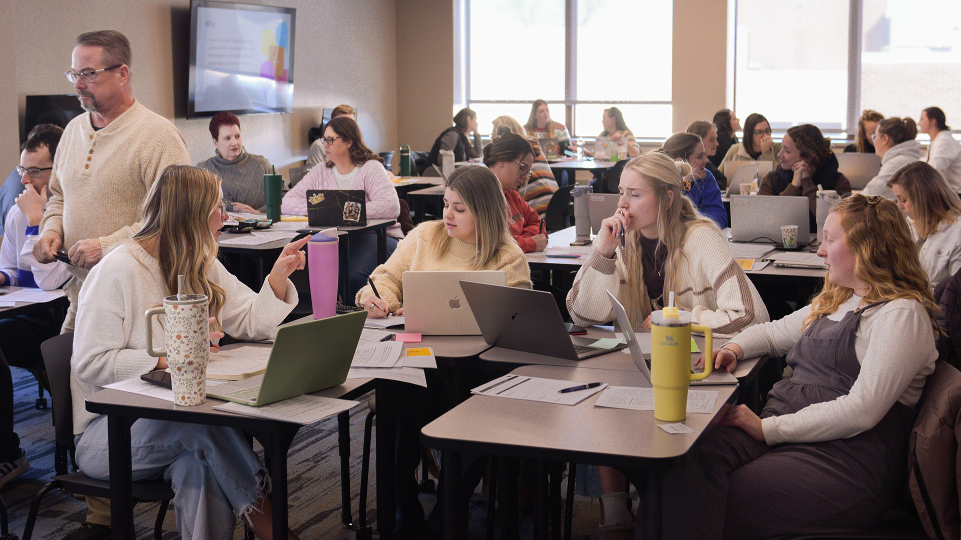 Educators engage in discussions at small tables inside a VCSU classroom