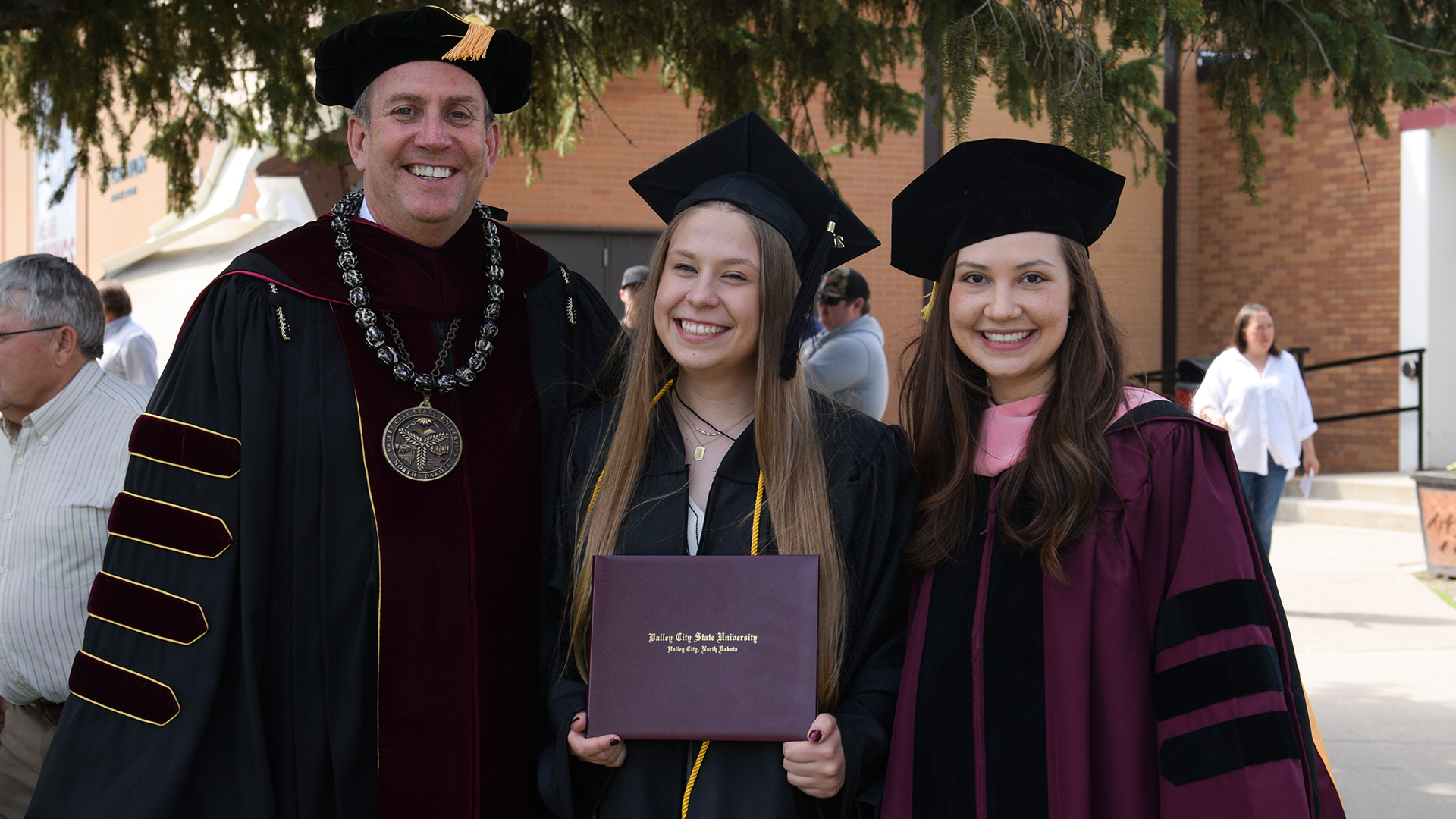 President Alan LaFave, faculty member Katrina Clements and student Tedi Dimmer smile together after the 2024 spring commencement.