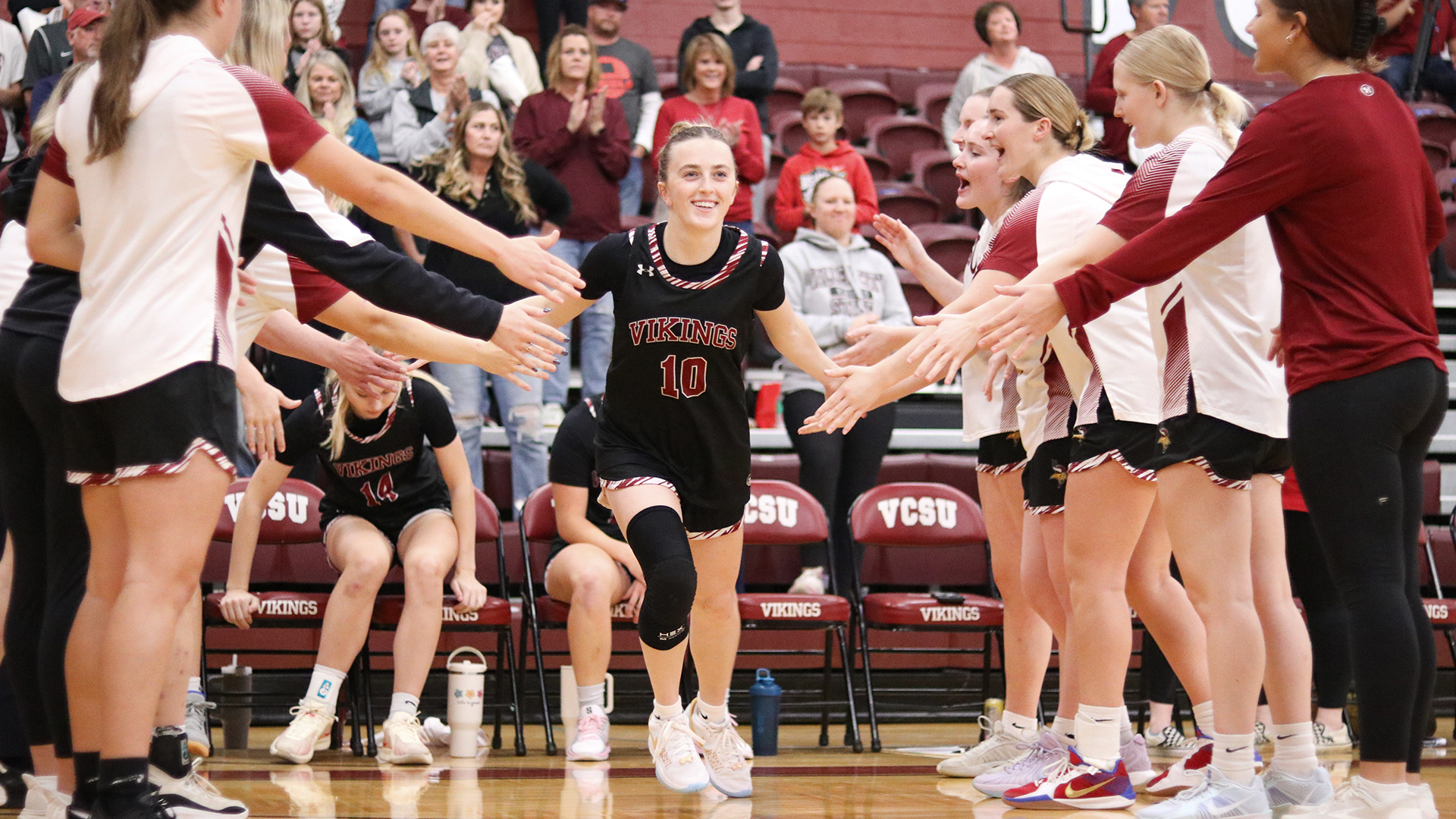 VCSU basketball player Ellie Braaten runs through a line of teammates during starting lineup announcements.