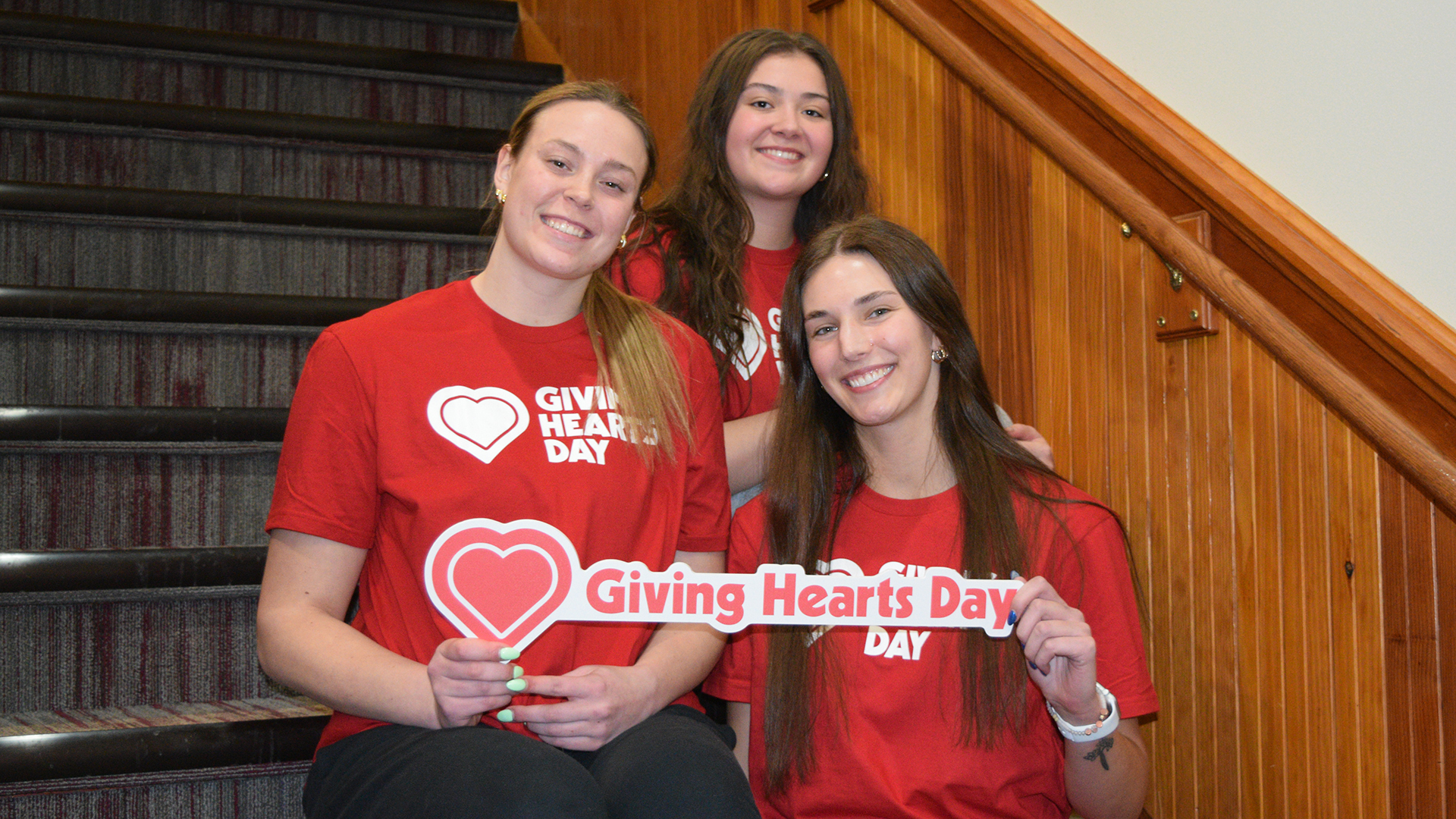 3 VCSU students hold up a sign that says "Giving Hearts Day"