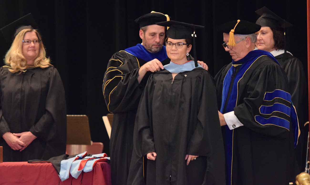 A masters degree graduate recieves a hood