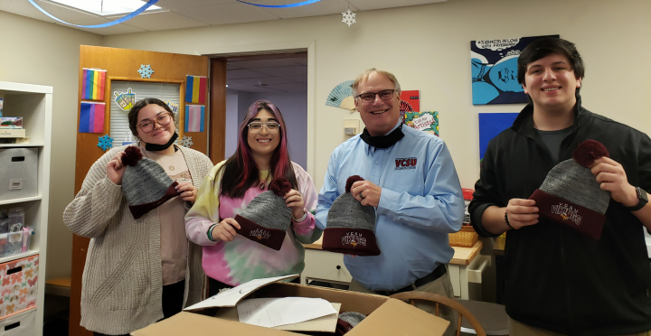 Students receiving hats from Rick Ross
