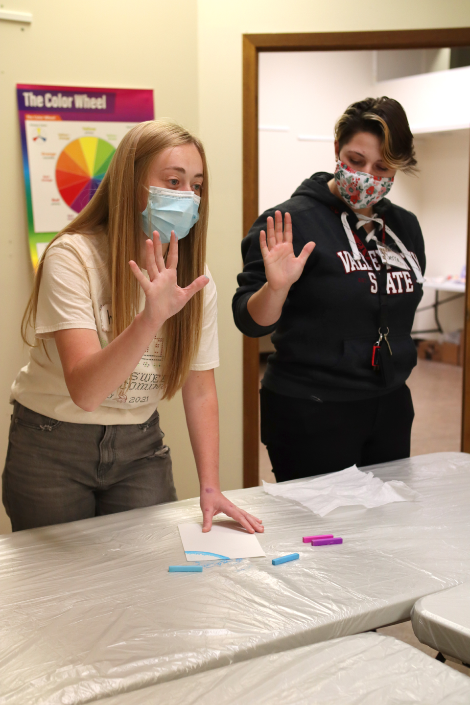 Valley City State University students demonstrate how pastels color your fingers while using them in an art project.