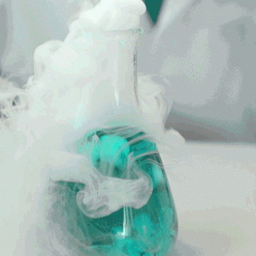 Materials react in a scientific environment creating smoke in a beaker.