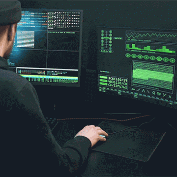 Man looking between two screens, working on programming