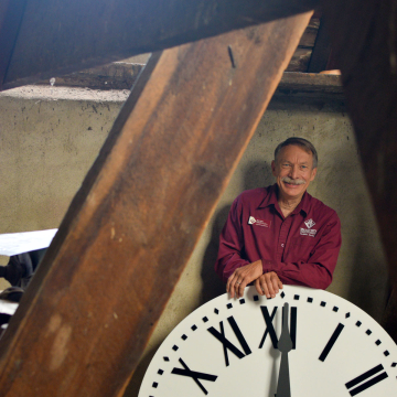 VCSU Facility Services member Daryl Heise stands with the new acrylic clock face in the clock tower.