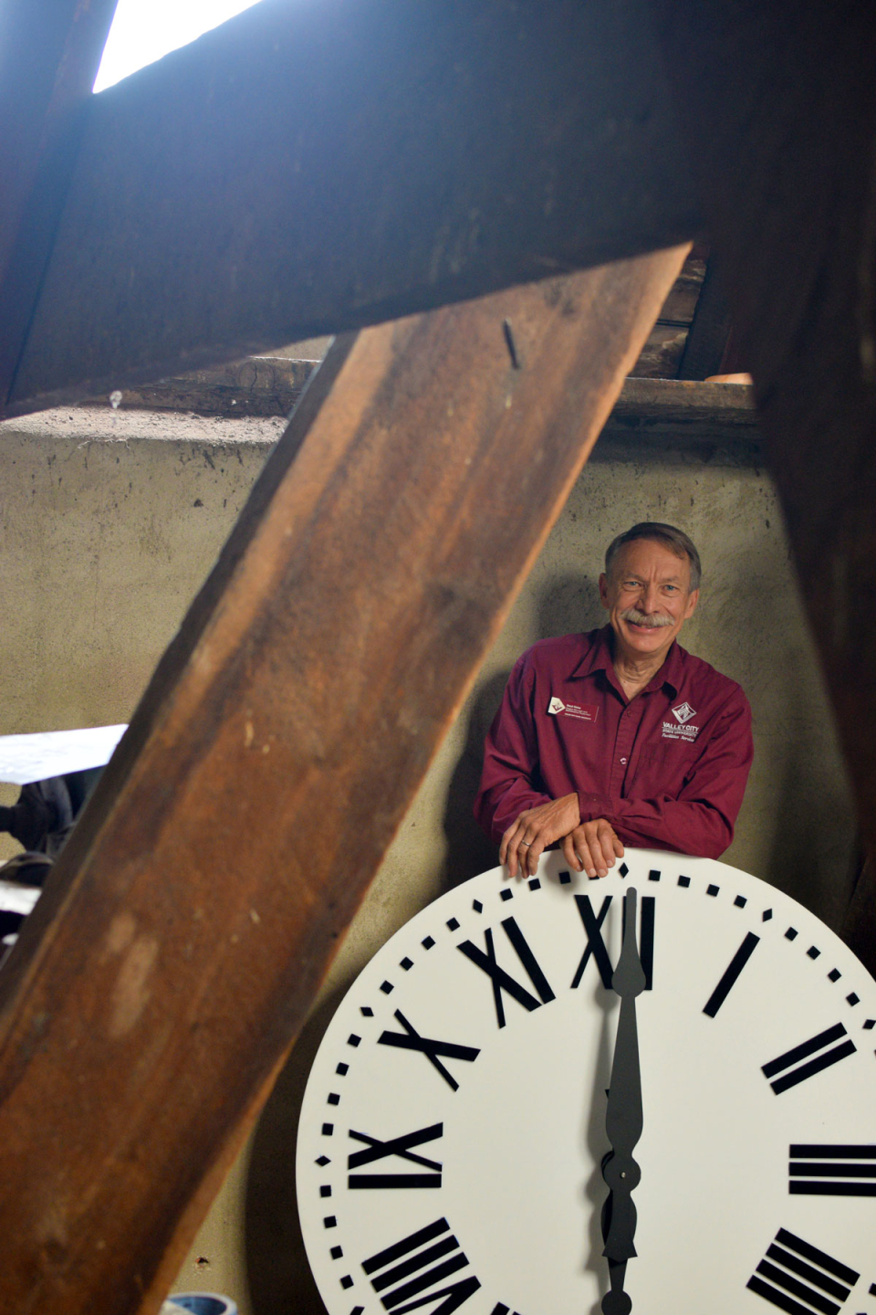 VCSU Facility Services member Daryl Heise stands with the new acrylic clock face in the clock tower.