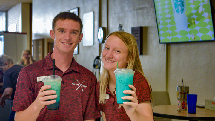 male and female student smiling at camera holding Zinger drinks from Viking Grounds