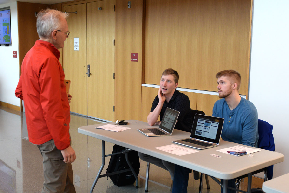 Students speaking with a faculty member about their research during the scholar symposium.
