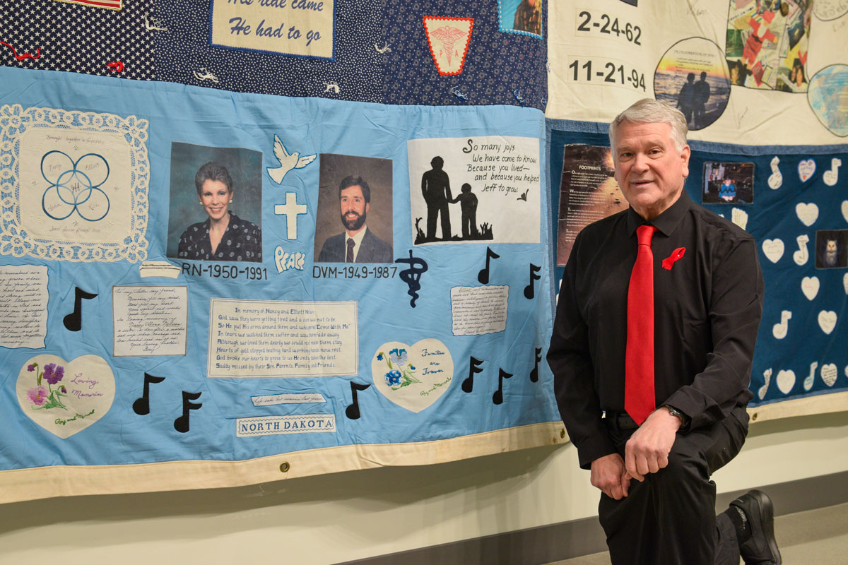 A photo of Dr. Gary Ketterling with the panel on the AIDS quilt in memory of his sister Nancy.