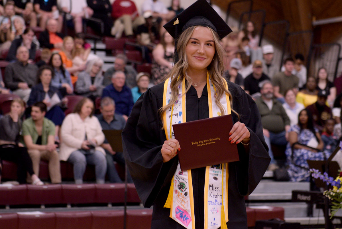 A graduate of Valley City State University posing with her diploma.