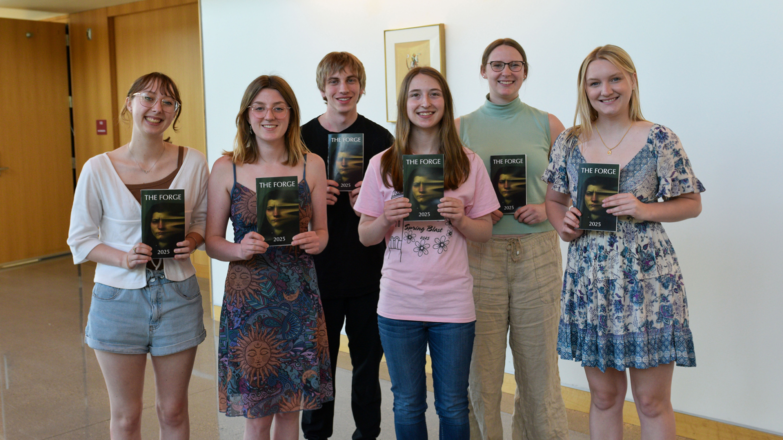 The 6 student editors of The Forge hold up copies of the 2025 magazine.