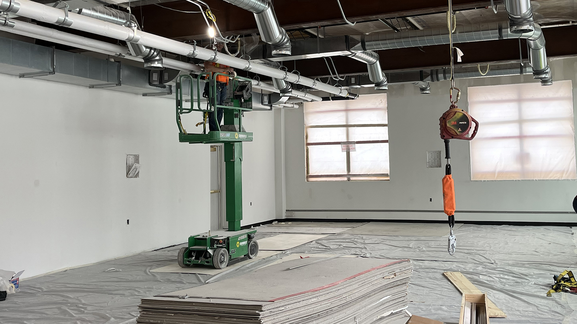 A 3rd floor classroom is shown with a lift for working on the ceiling; the carpet is laid but covering in protective plastic.