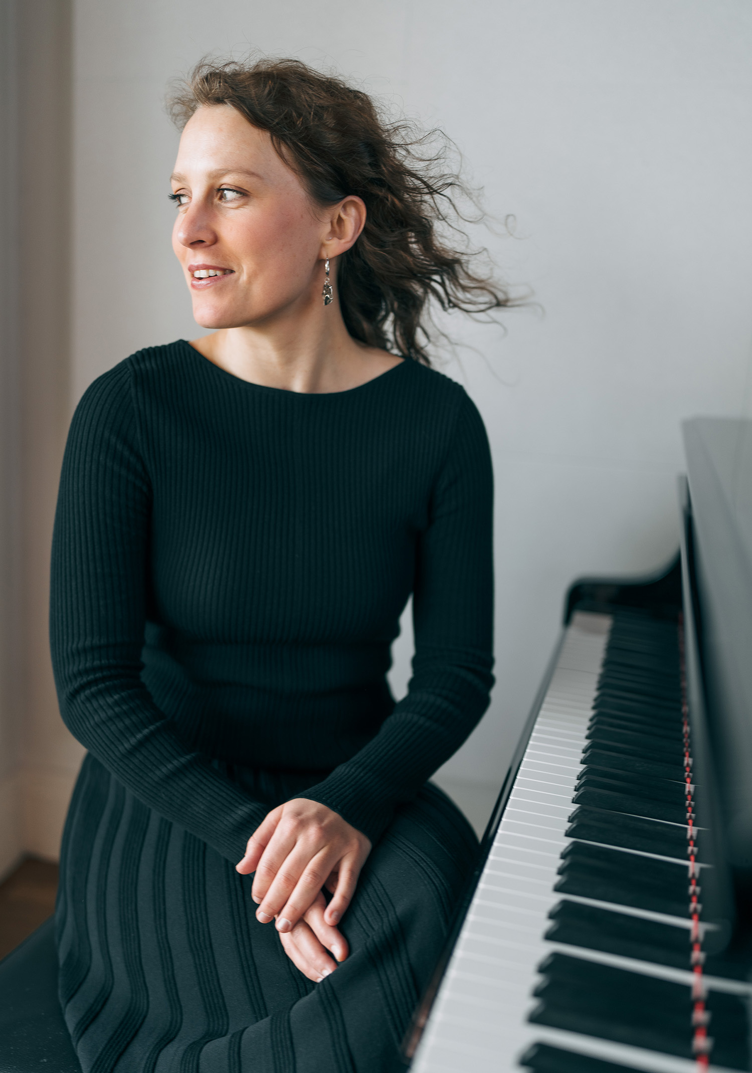 Oda Voltersvik sits at a piano while wearing a green dress
