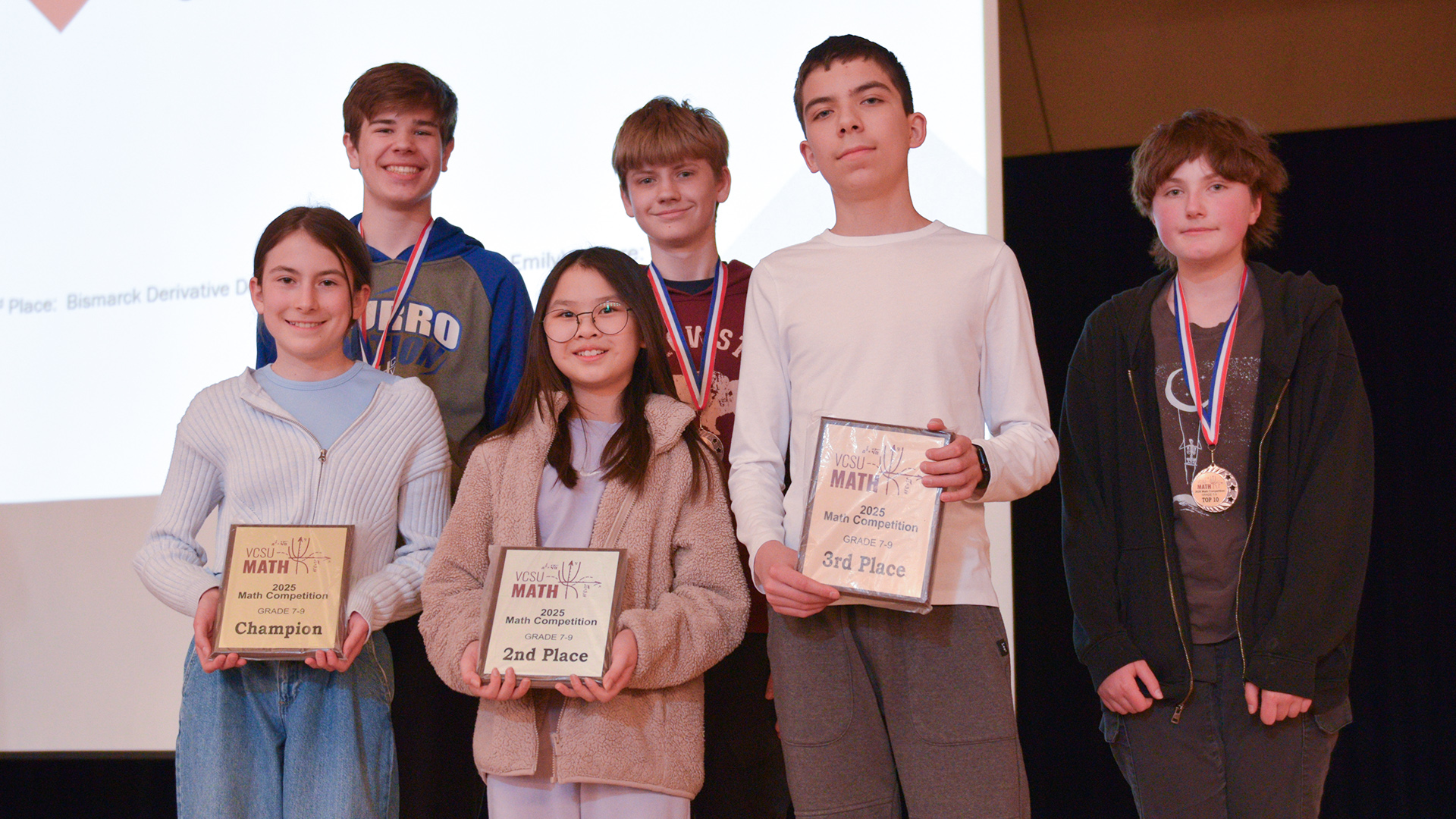 Six students hold plaques and medals for individual awards