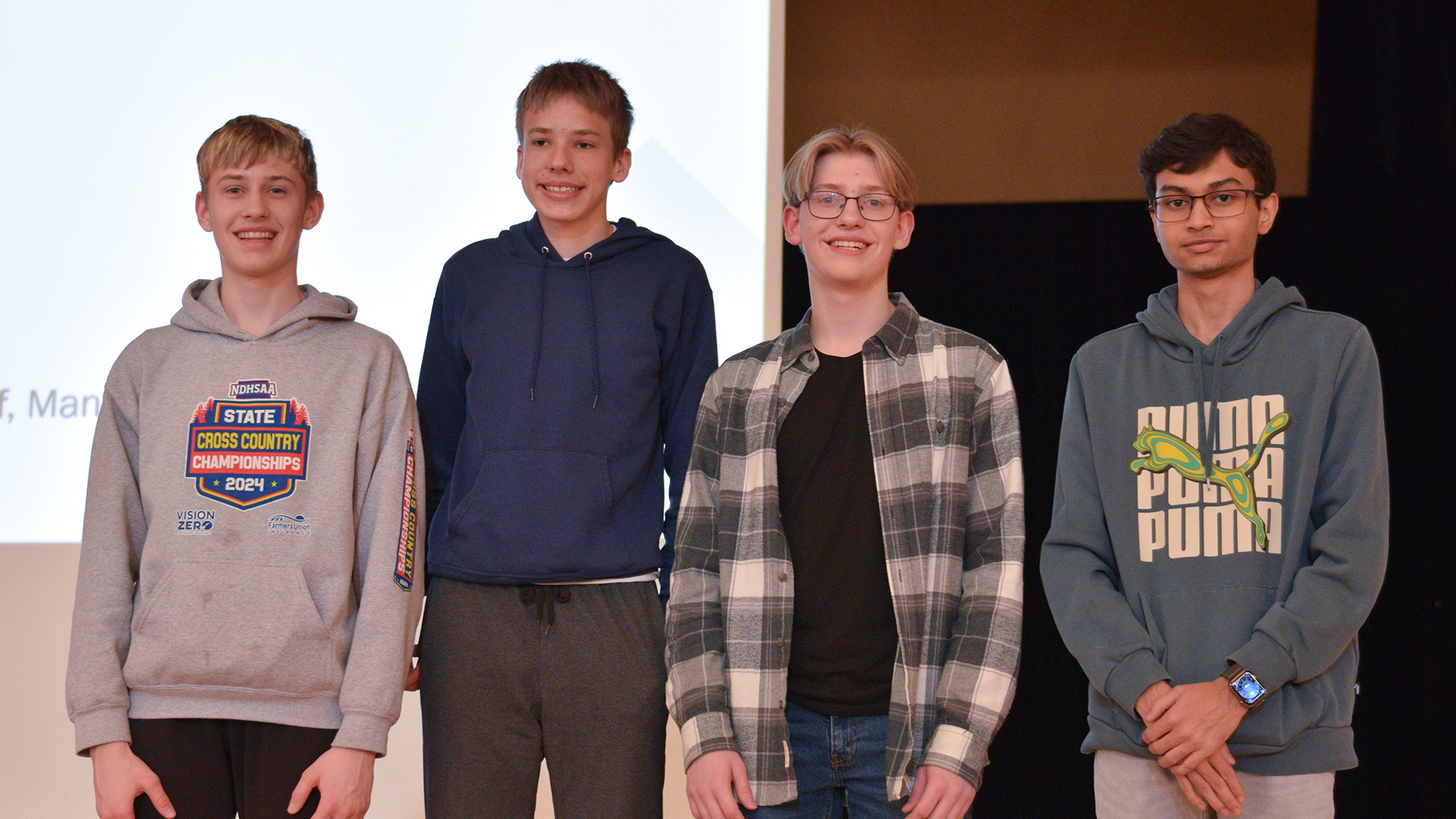 Four students are recognized on a stage for a team award