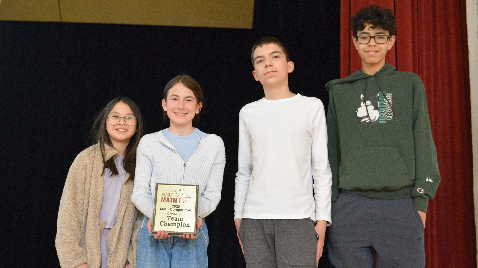 Four students hold a plaque that says Team Champion