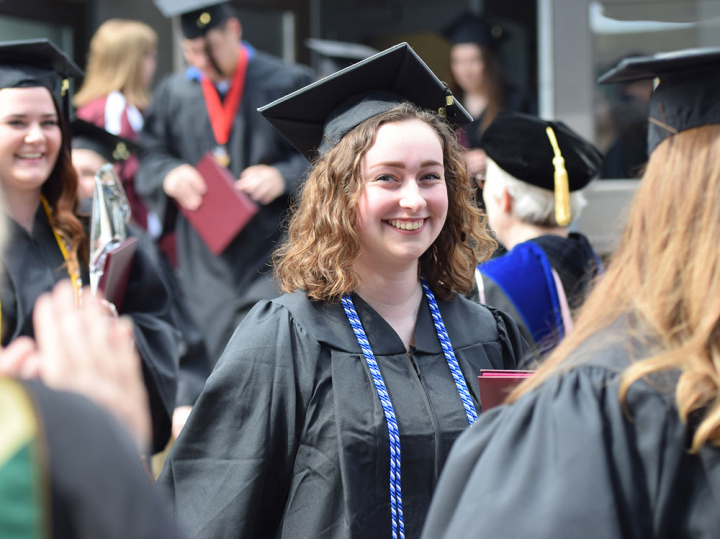 A graduate looks at the camera with a smile