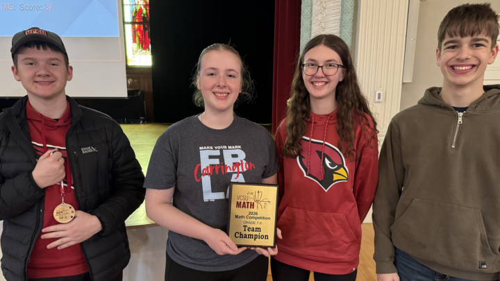 A team of 4 students holds up a first place plaque