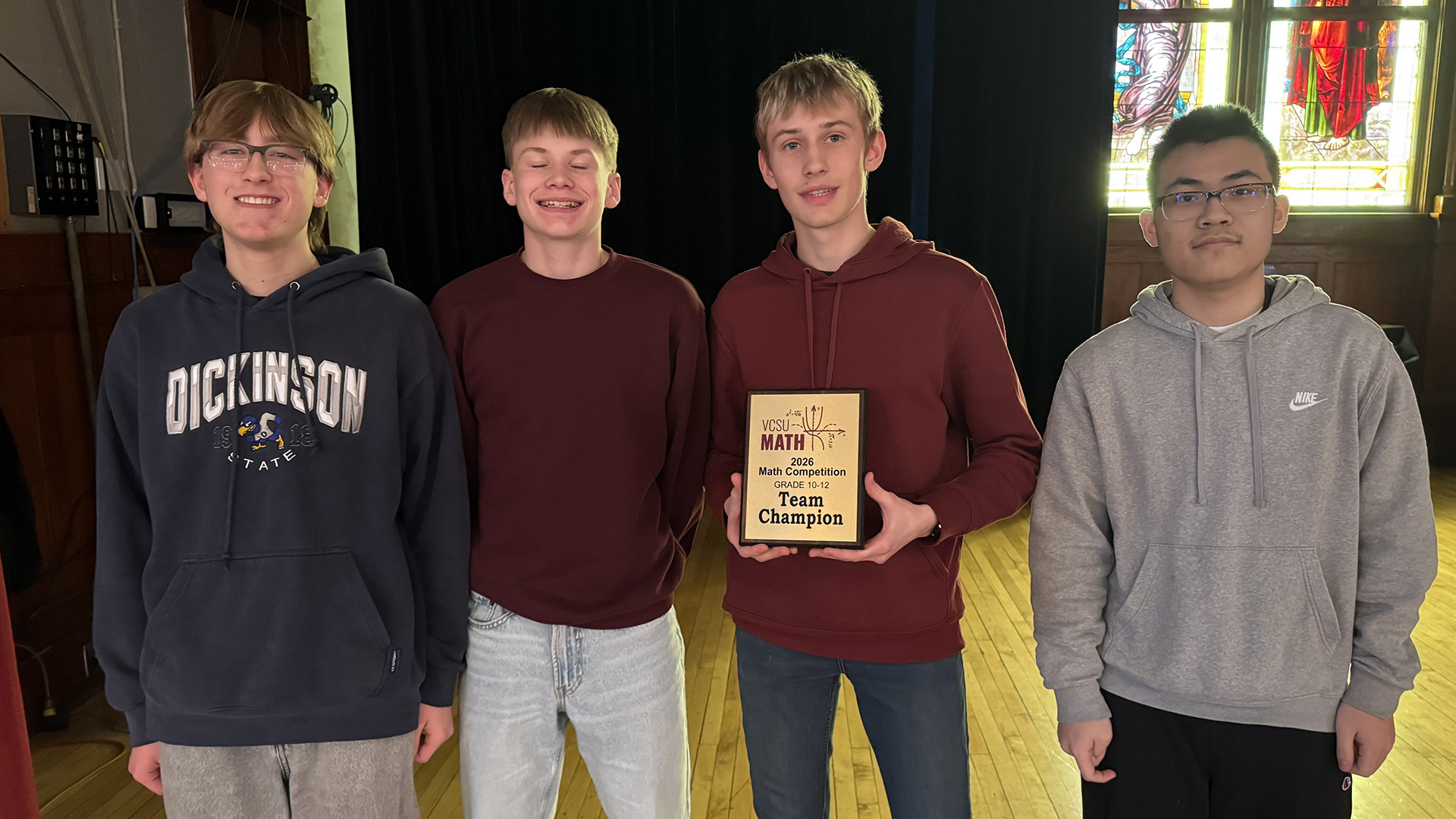 A team of four students hold up a first place plaque