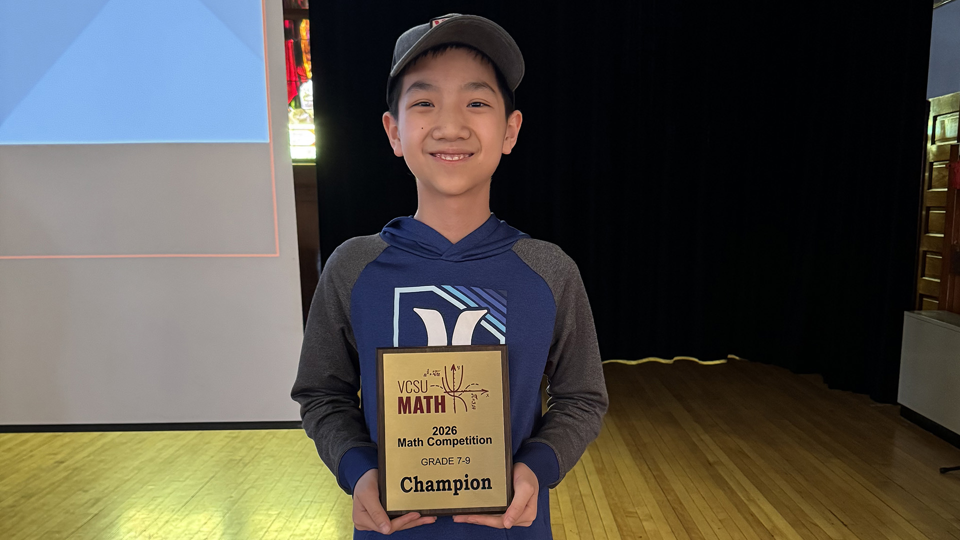 A male student holds up a first place plaque