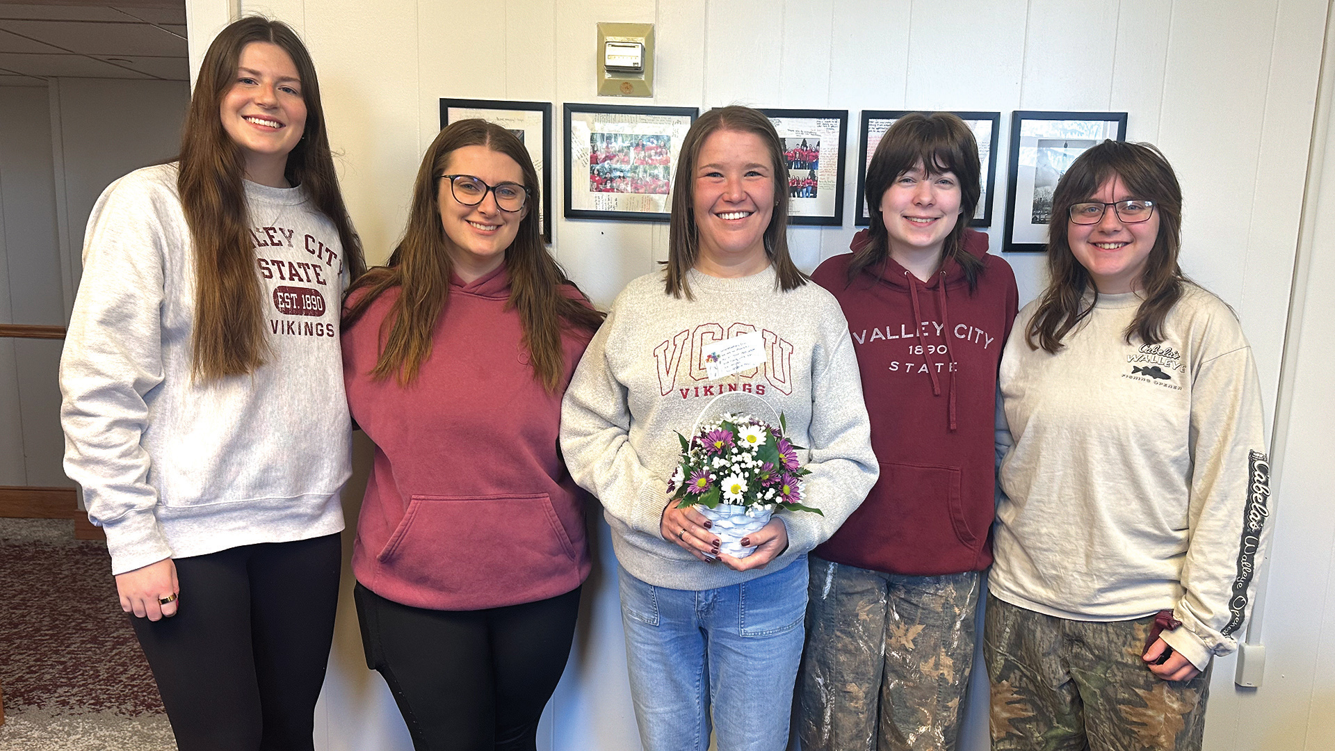 4 female students present a pot of flowers to Erin Edinger