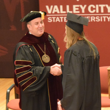 president and graduating student in Vangstad Auditorium