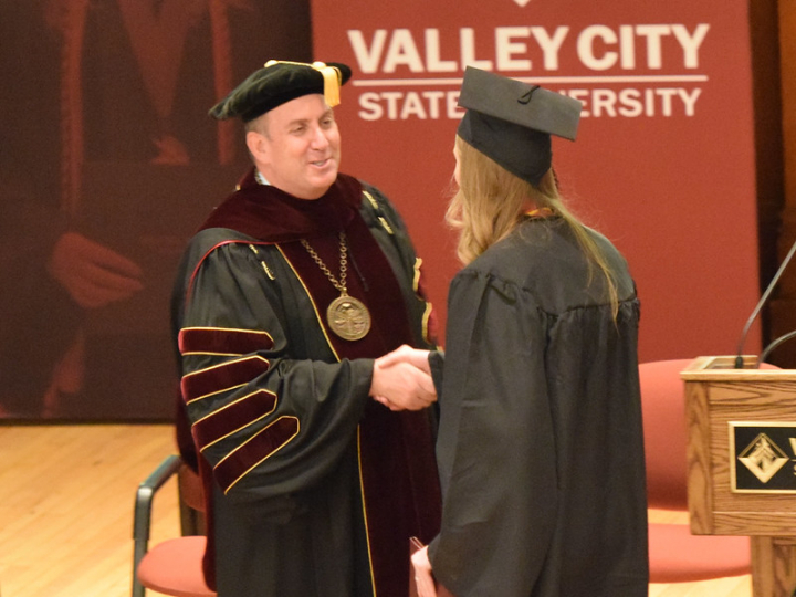 President Alan LaFave and graduating student in Vangstad Auditorium