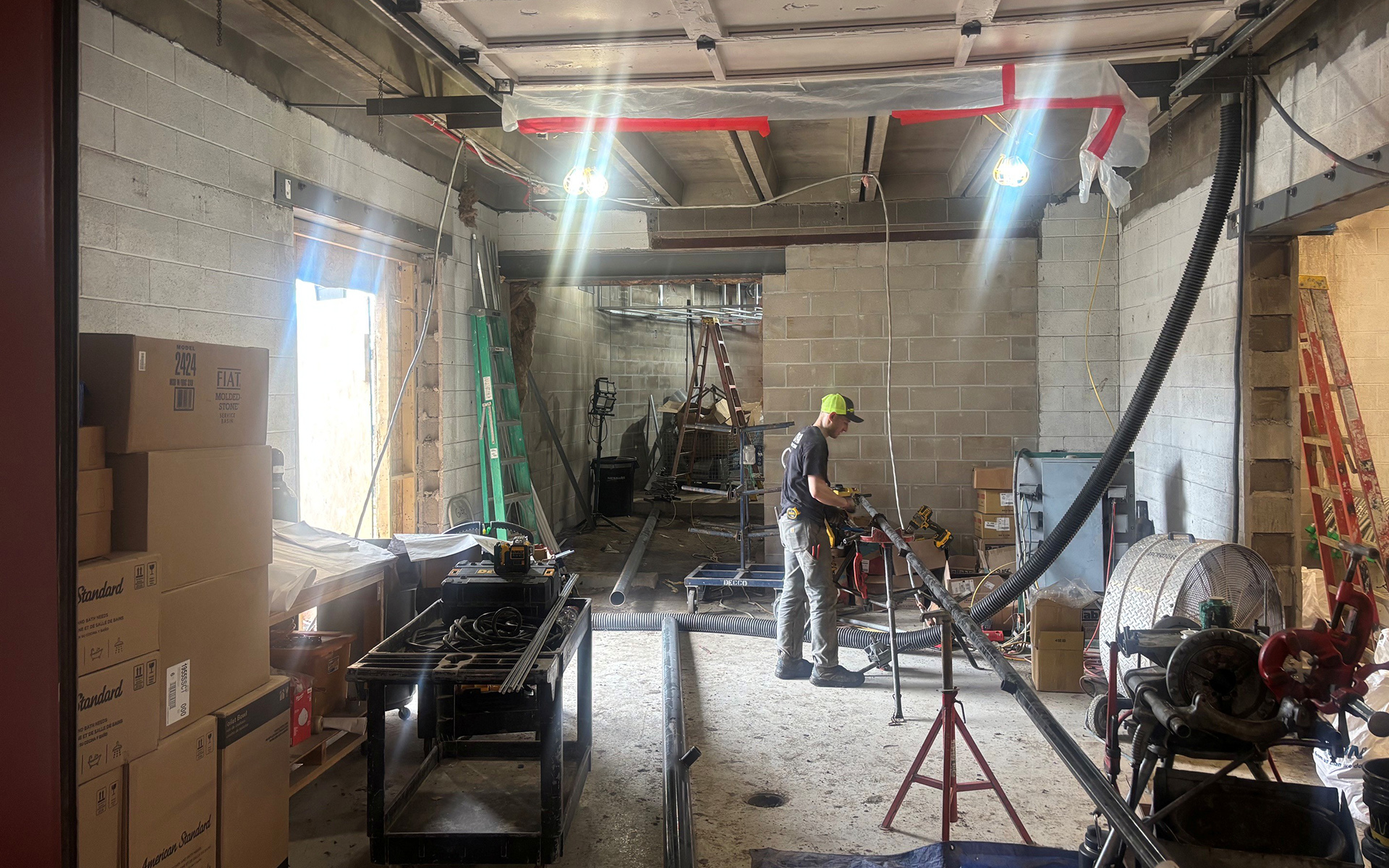 Construction equipment and a worker are pictured in an old garage undergoing renovation.