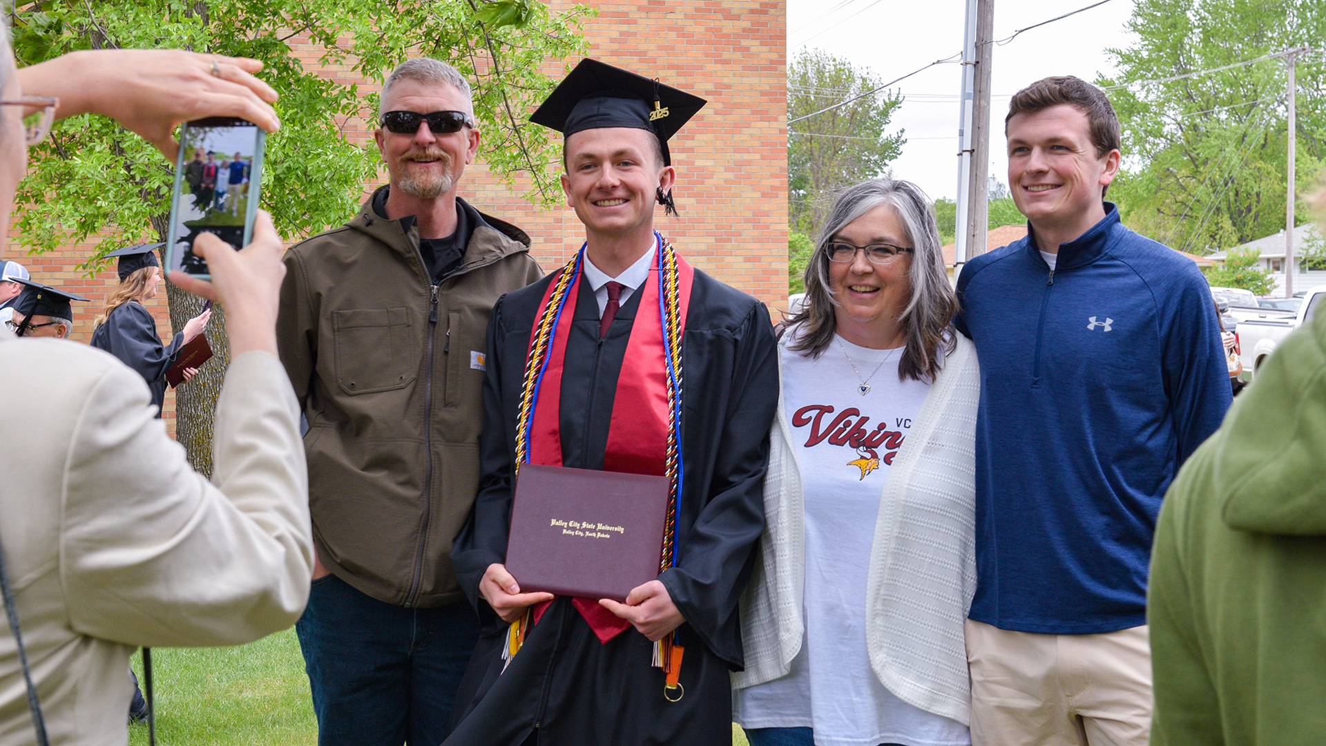 A VCSU family poses for an outside photo with their graduate after the spring commencement.