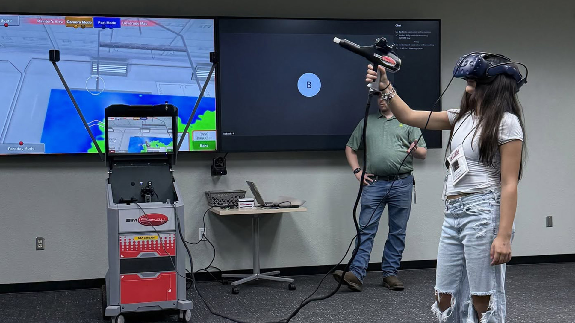 A student has on virtual reality goggles and holds a virtual reality paint gun as part of a training program at John Deere.