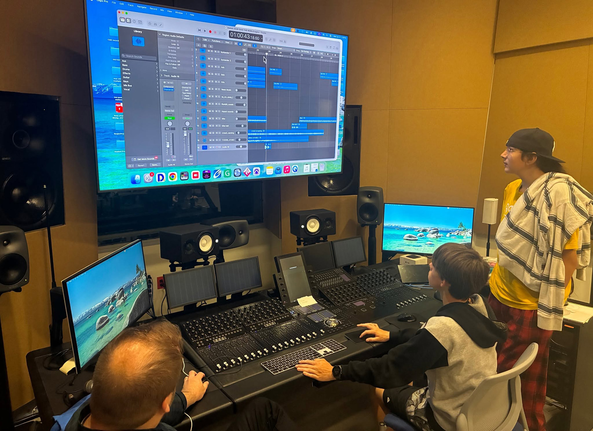 Students sit at a desk with buttons and sliders as they edit sound.