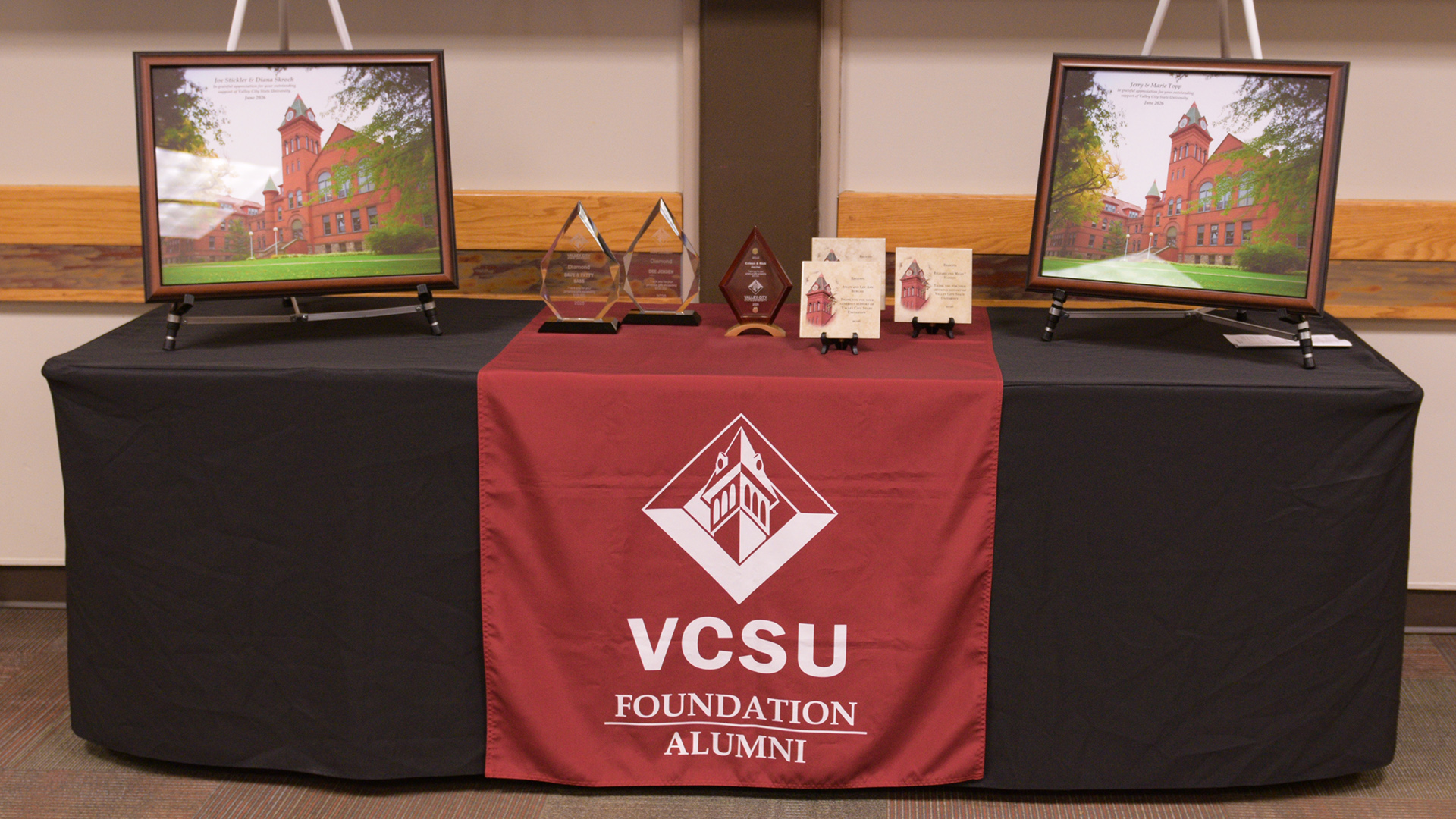 Donor awards, including plaques and photos, are displayed on a black tablecloth.