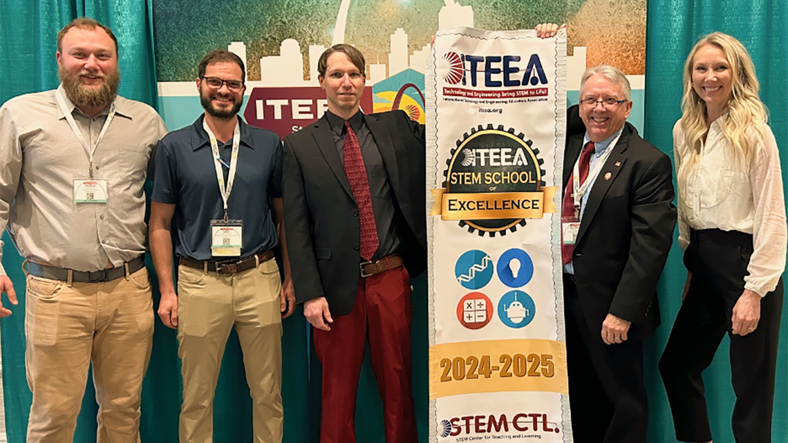 Andrew Coe, Dan Catizone, Clay Mannie, Peder Gjovik, and Lisa Krumwiede accept the ITEEA STEM School of Excellence banner for their respective schools.
