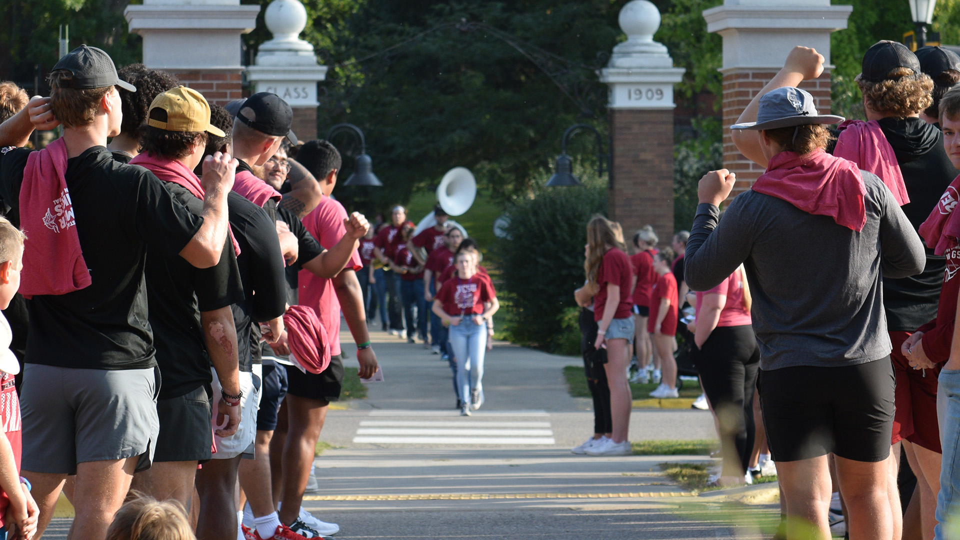 The VCSU Marching Band walks towards downtown between two groups of VCSU students