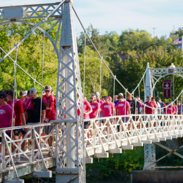 A large group of VCSU students walk across the campus Walk Bridge