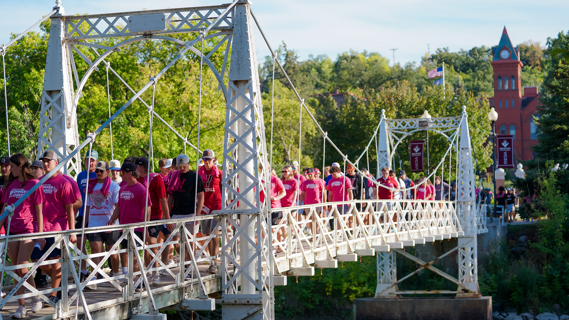 A large group of VCSU students walk across the campus Walk Bridge