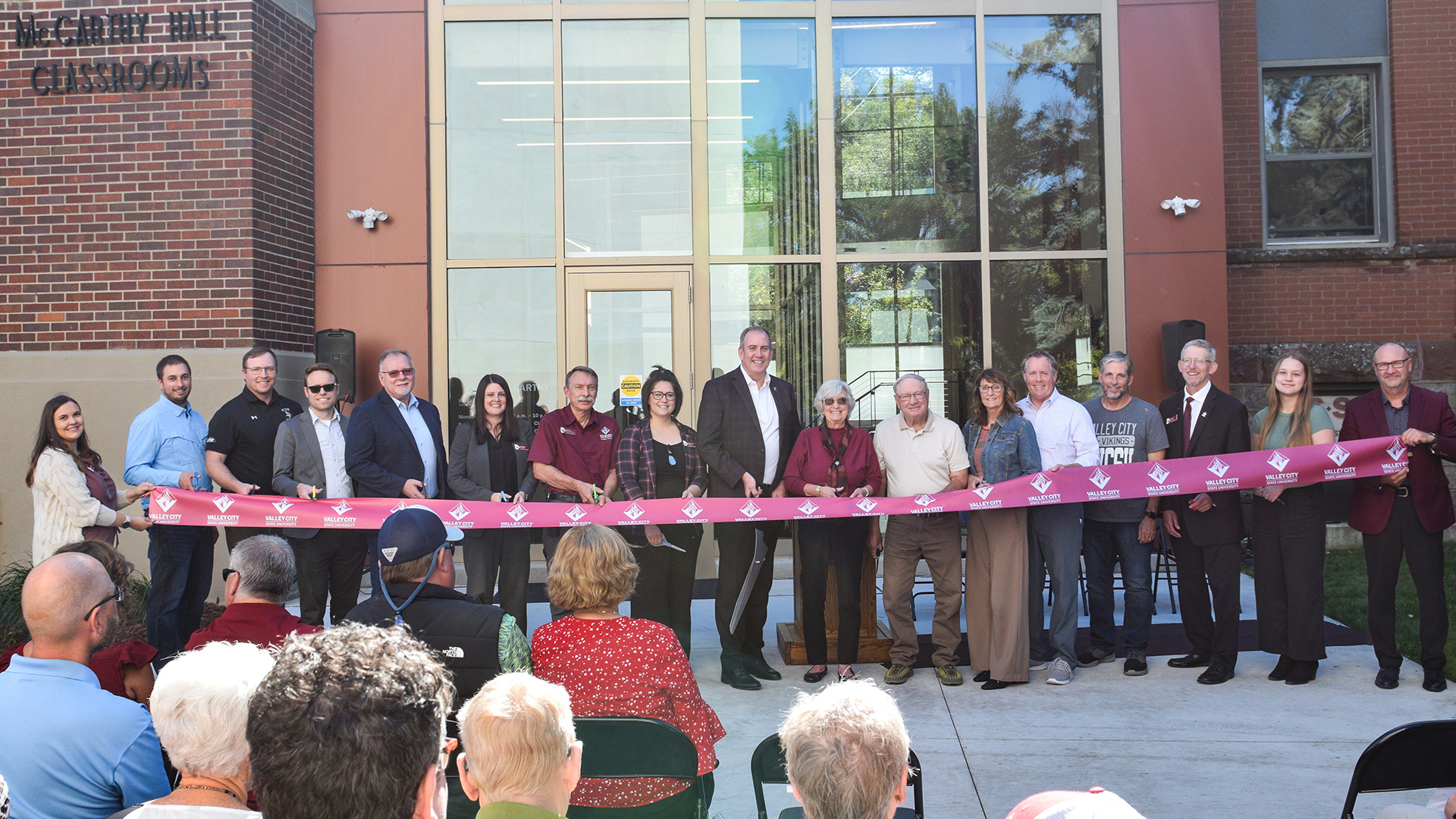 VCSU employees, building committee members and donors prepare to cut a ribbon in front of McCarthy Hall.