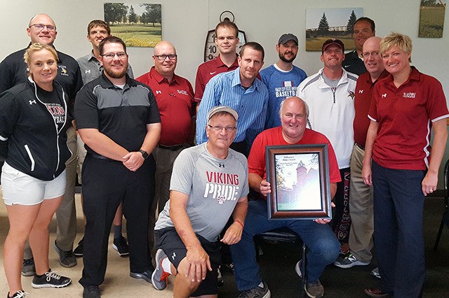 Pictured with Kevin Kamphuis (seated front right), are Jill DeVries, VCSU athletic director (right), and a host of Viking coaches, including (l to r) Casey Olney, Jenelle Trautmann, Josh Mower, Chad Smith, Gregg Horner, Dave Rausch (kneeling), Karl Sorby, Daniel Scheff, Ryan Montgomery, Michael Mook, Jason Kremer and Dennis McCulloch.