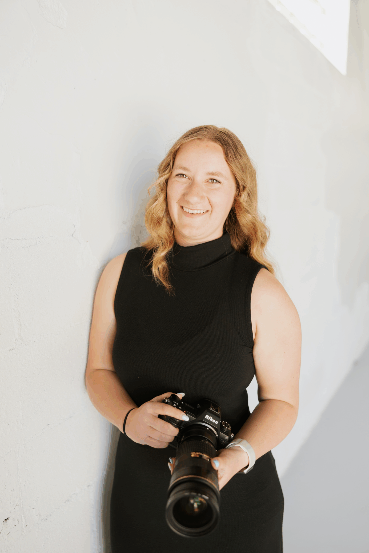 Alyssa Thomsen holding a camera smiling at the camera